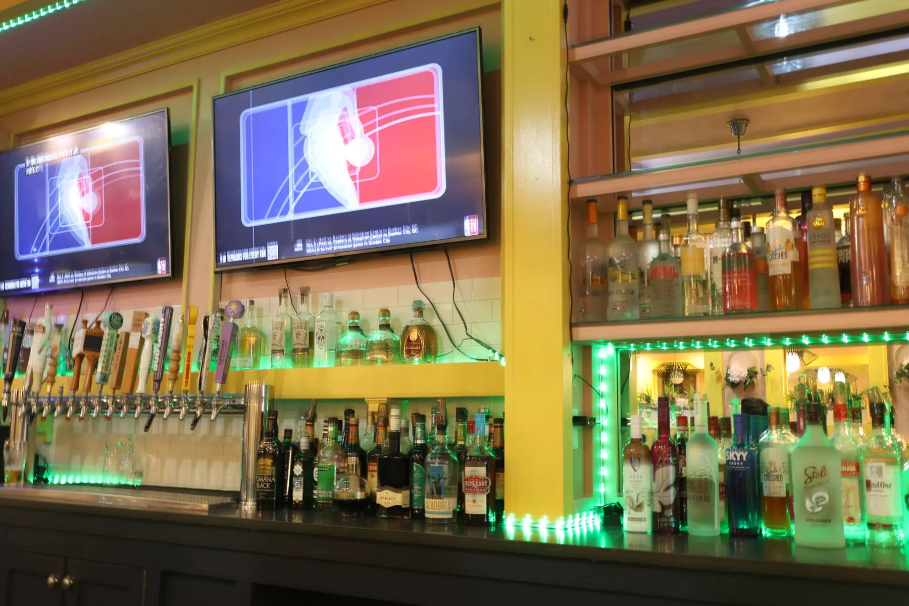 Royal Mint bar, lit in green with taps and bottles